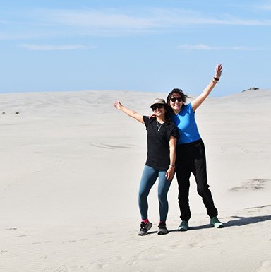 Diversión en las dunas, dos Camilas en libertad Dos mujeres sonrientes en las dunas de arena en Nueva Zelanda