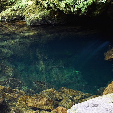 Lago de aguas puras en Nueva Zelanda Lago de agua transparente con piedras visibles, en entorno montañoso.