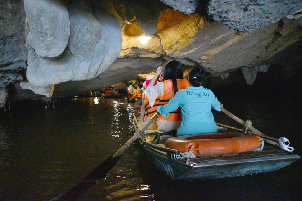 Bote de remos con pasajeros ingresando al interior de una cueva de piedra caliza en Ninh Binh.