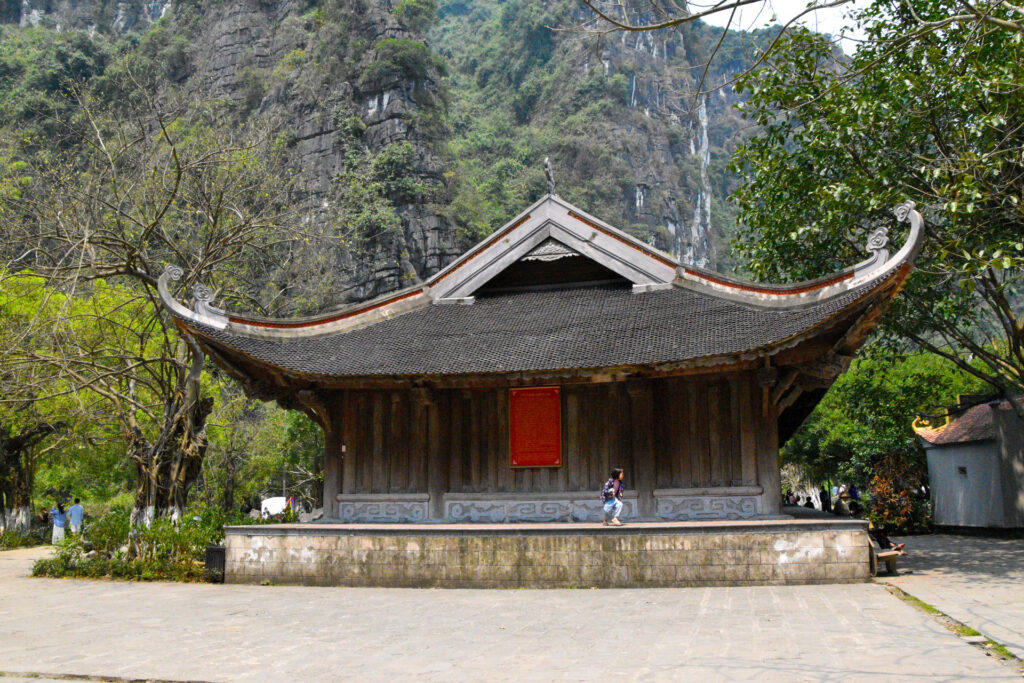 Templo de madera solitario con techos curvos rodeado de vegetación exuberante durante la Ruta en Ninh Binh Vietnam.