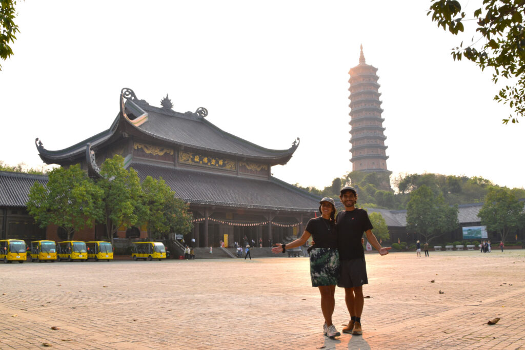 Camila y John posando juntos en una explanada con templos y una pagoda al fondo en Ninh Binh.