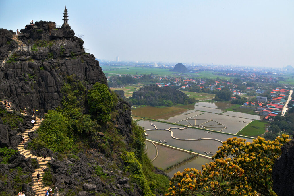 Sendero de escaleras de piedra que sube por la ladera de una montaña hacia una pagoda.